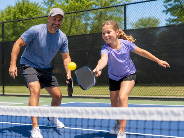 Adult and child playing pickleball together