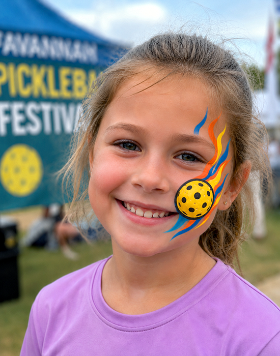 Child smiling with pickleball-themed face paint